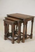 A nest of three oak occasional tables, raised on turned column supports, 19" x 13" x 19"