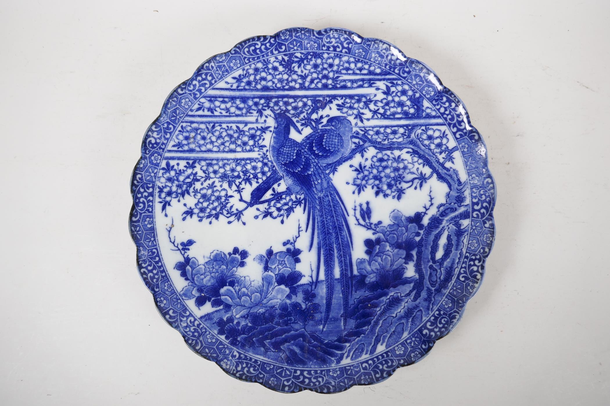 A Japanese blue and white charger with petal shaped edge, decorated with asiatic birds in prunus