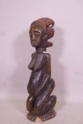 An antique African carved wood fertility figure with beaded headdress and inset with sea shells,
