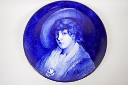 A blue and white pottery charger with painted portrait of a young girl, detailed verso D. Simpson