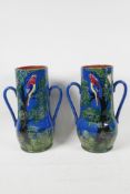 A pair of Devon pottery two handled red ware vases painted with parrots in a tree, 10" high