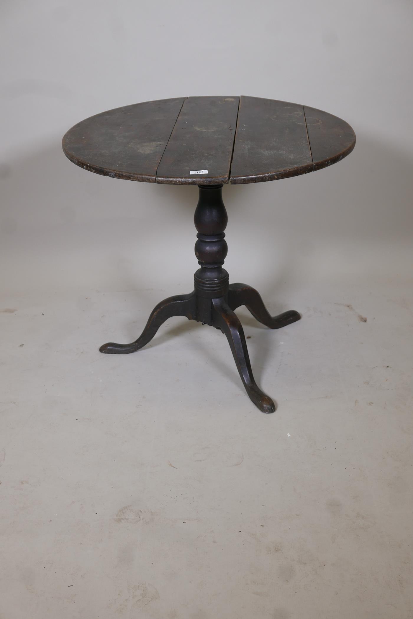 An C18th oak tilt top table raised on a turned column and tripod supports, (top fixed), 30" diameter