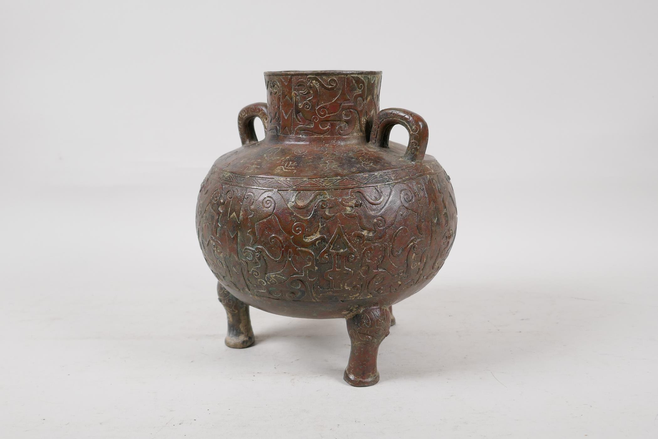 A Chinese bronze two handled vase raised on tripod supports, with raised and engraved archaic - Image 4 of 7