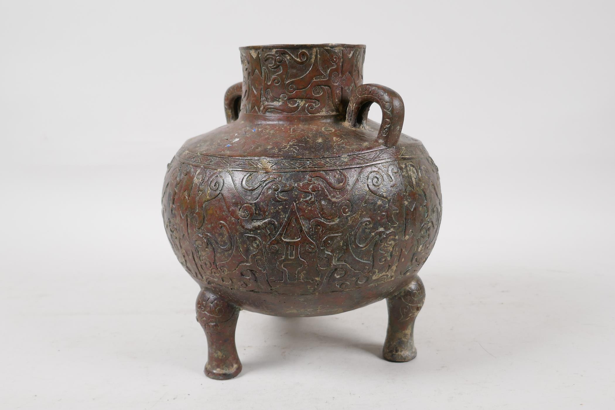 A Chinese bronze two handled vase raised on tripod supports, with raised and engraved archaic - Image 2 of 7