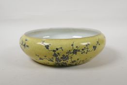 A Chinese yellow glazed porcelain bowl with a rolled rim and black and white floral decoration, seal