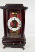 A cased skeleton clock with white enamel chapter ring and Roman numerals, 15" high