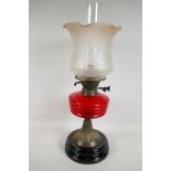 A C19th brass and glass oil lamp with cranberry glass shade, 21" high