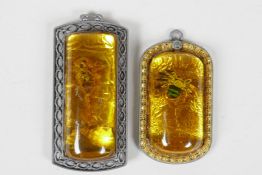 A Chinese amber style pendant in a metal mount, containing a scorpion, and another similar,