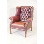 A C19th buttoned wing back armchair in red leather