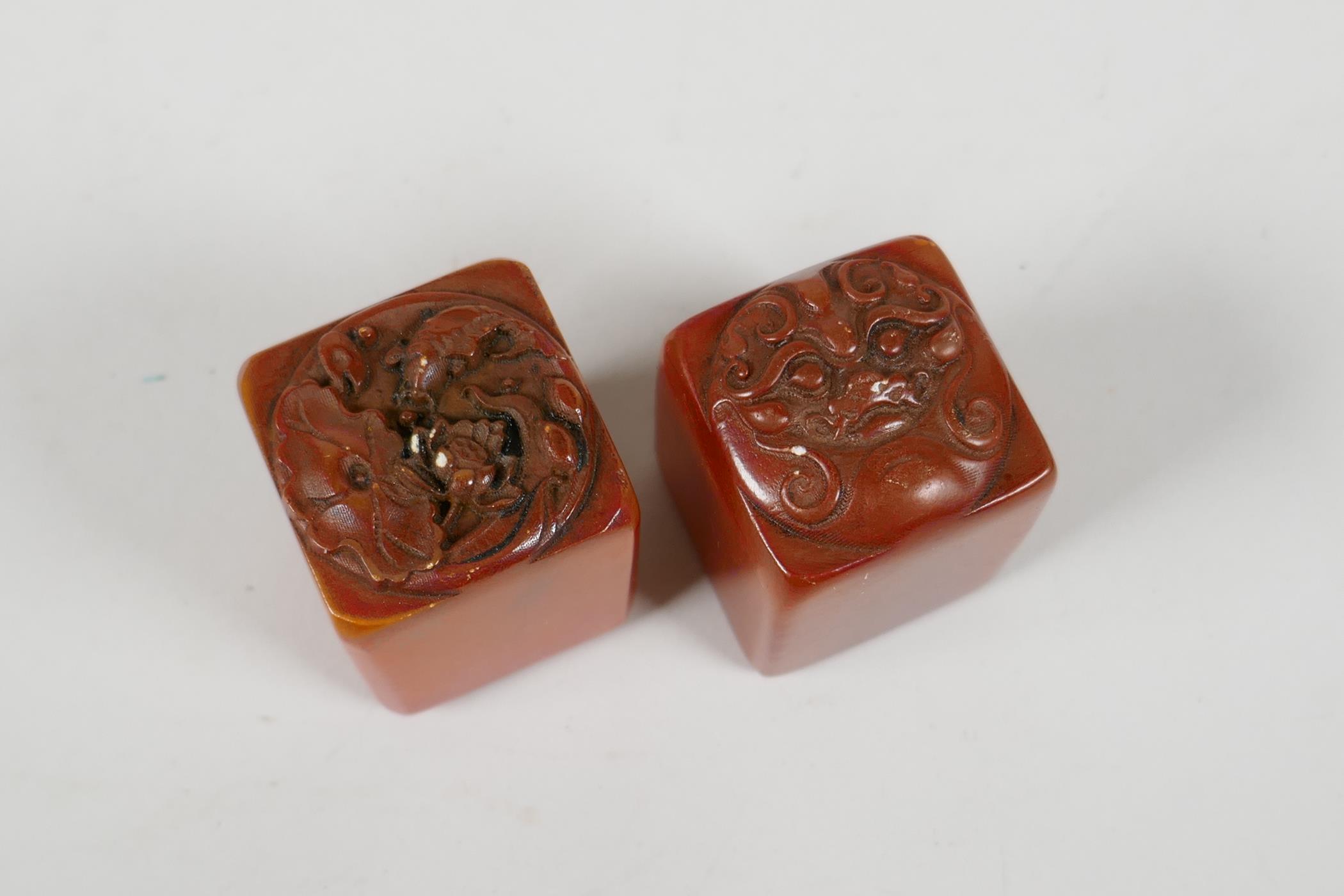 A pair of Chinese amber soapstone seals, decorated with carp, lotus flowers & a dragon head, 1½" - Image 2 of 3