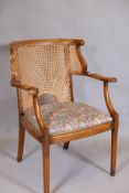 A 1930s bergere elbow chair, with shaped arms, back, cane back and seat