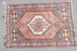 A full pile grey ground Afghan Belouch nomadic rug with pink medallion design and pink border, A/F