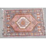 A full pile grey ground Afghan Belouch nomadic rug with pink medallion design and pink border, A/F