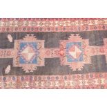 A Persian black ground hand woven wool runner with a repeating rust coloured medallion design within