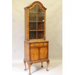 A Queen Anne style figured walnut bookcase, the arched top with single door and adjustable