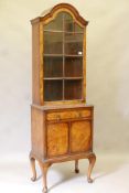 A Queen Anne style figured walnut bookcase, the arched top with single door and adjustable