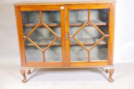 A 1930s golden walnut bookcase with two astragal glazed doors, raised on cabriole supports, 12" x