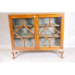 A 1930s golden walnut bookcase with two astragal glazed doors, raised on cabriole supports, 12" x