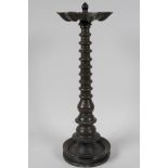 An early Indian bronze column oil lamp, with the seven burner head on a tapered ring, turned column