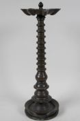 An early Indian bronze column oil lamp, with the seven burner head on a tapered ring, turned column