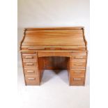 A 1930s oak roll top pedestal desk with nine drawers and slides to each pedestal, serpentine tambour