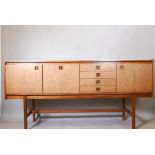 A mid century Danish style rosewood veneered sideboard with recessed drawer pulls, raised on moulded