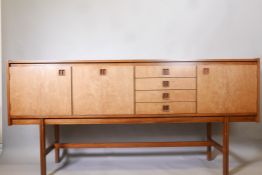 A mid century Danish style rosewood veneered sideboard with recessed drawer pulls, raised on moulded