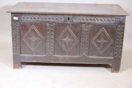 An C18th triple panel carved oak coffer, with panelled ends and plank top, raised on stile supports,