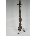 A turned bronze candlestick on a tripod base, 28" high