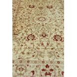 A vintage wool carpet with all over oriental inspired design in faded reds and ochres on a buff