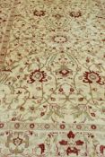 A vintage wool carpet with all over oriental inspired design in faded reds and ochres on a buff