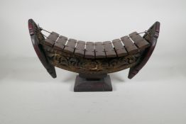 An Oriental carved & painted wood xylophone, 19½ long