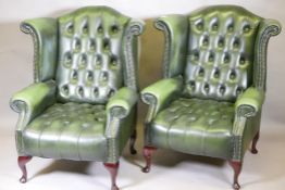 A pair of buttoned leather wingback armchairs, with brass stud detail, raised on cabriole supports