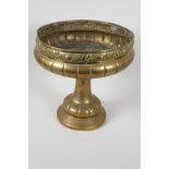 A C19th brass pedestal fruit bowl, the rim embossed with various fruits, 10" high, 10" diameter