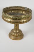 A C19th brass pedestal fruit bowl, the rim embossed with various fruits, 10" high, 10" diameter