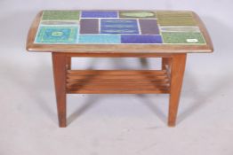 A mid century teak two tier occasional table with inset tile top and slatted undertier, raised on