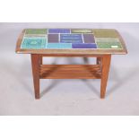 A mid century teak two tier occasional table with inset tile top and slatted undertier, raised on