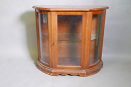 A mahogany display cabinet with bow ends and single door, raised on a plinth base, 38" x 16" x 34"