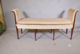 A C19th bow fronted window seat, with scroll arms, raised on square tapering supports, with spade