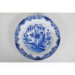 An C18th/C19th Delft blue and white charger with hand painted floral decoration, 14" diameter