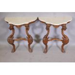 A pair of serpentine shaped carved wood console tables with marble tops, raised on winged griffin