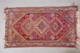 A Persian wool rug with a central triple medallion design on a tomato red field, 31" x 57"