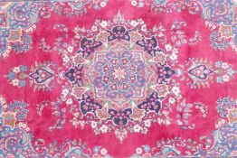 A pink/red ground Persian Kashmar carpet with a floral medallion design, 77" x 117"