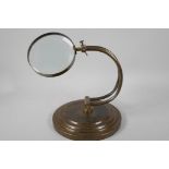 An industrial style table top magnifying glass on adjustable brass frame, glass 4" diameter