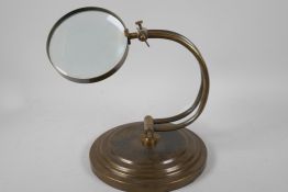 An industrial style table top magnifying glass on adjustable brass frame, glass 4" diameter