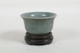 A Chinese celadon crackle glaze porcelain tea bowl, on a hardwood stand, 3" diameter