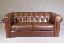 A leather button back Chesterfield settee, lacks feet, 73" wide
