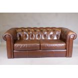 A leather button back Chesterfield settee, lacks feet, 73" wide