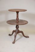 A George III mahogany two tier dumb waiter on a turned and carved column and tripod supports, A/F