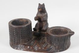 A Black Forest carved wood smokers stand, with tree stump ashtray and cigarette tub, and a seated